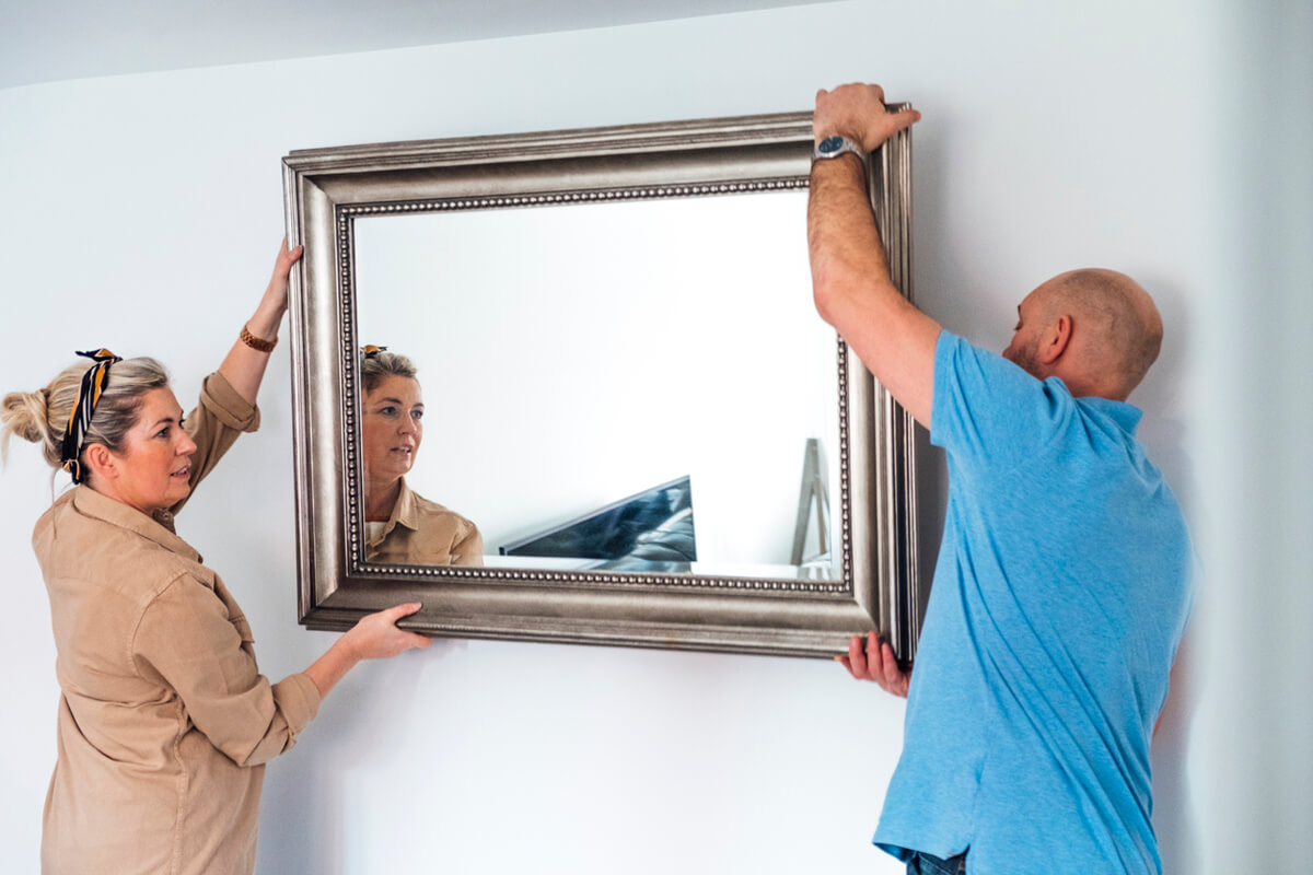 Couple haning a framed mirror